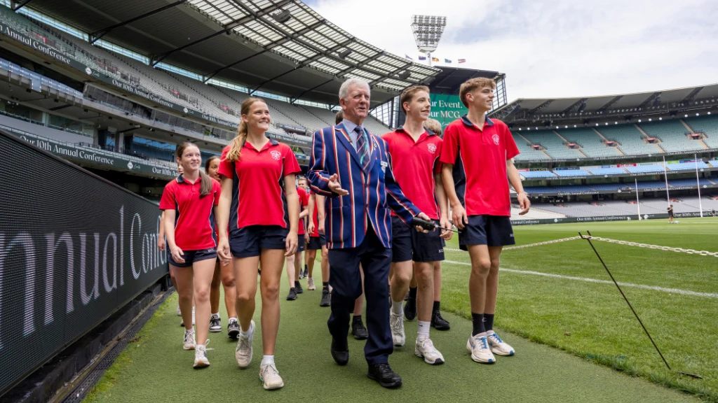 Tour guide and school students on the MCG boundary line