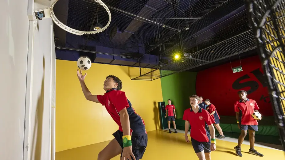 School children playing basketball on mini indoor court