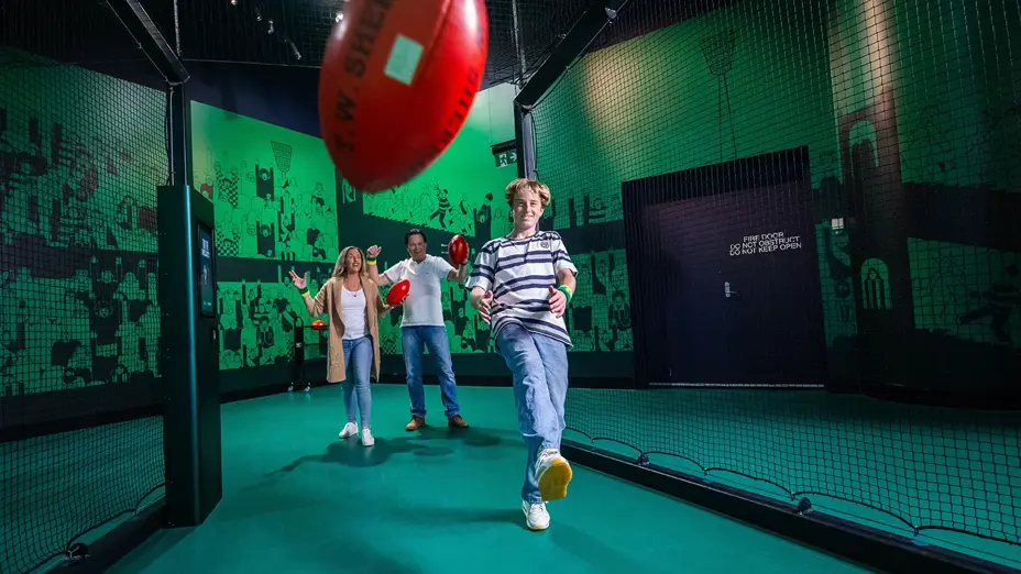 Family kicks footy in indoor nets