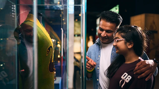 A father and daughter viewing a historic sports jersey on display