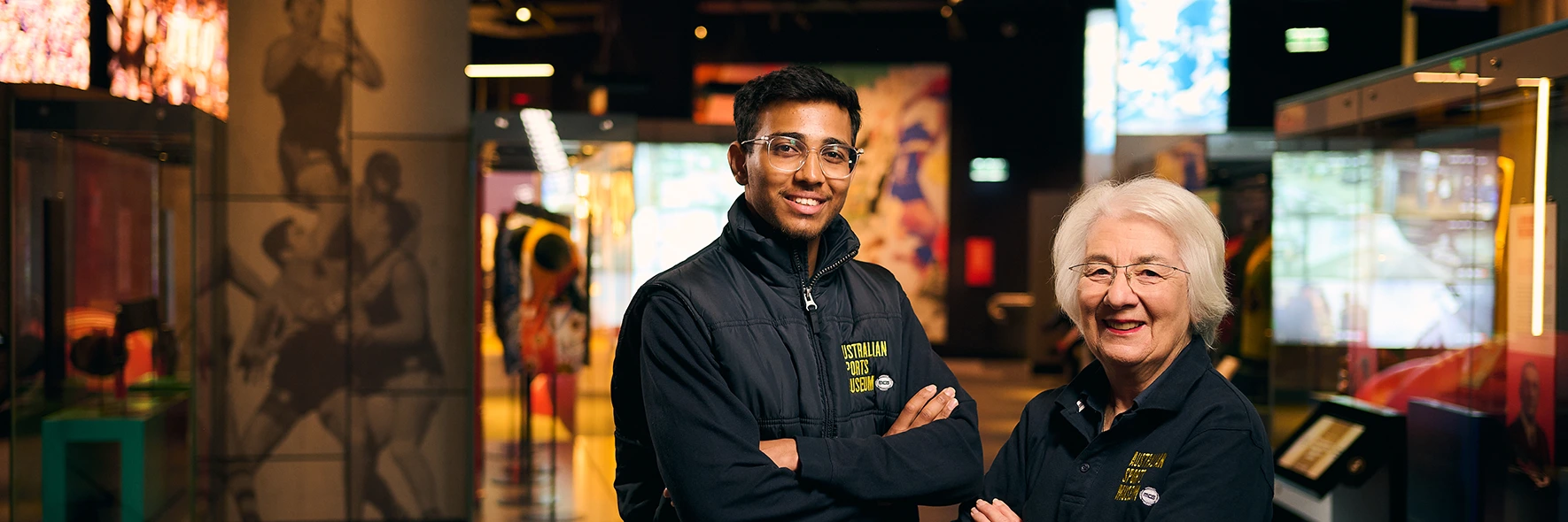 Two Australian Sports Museum staff standing together in gallery
