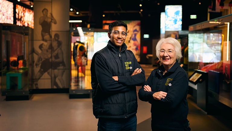 Two Australian Sports Museum staff standing together in gallery