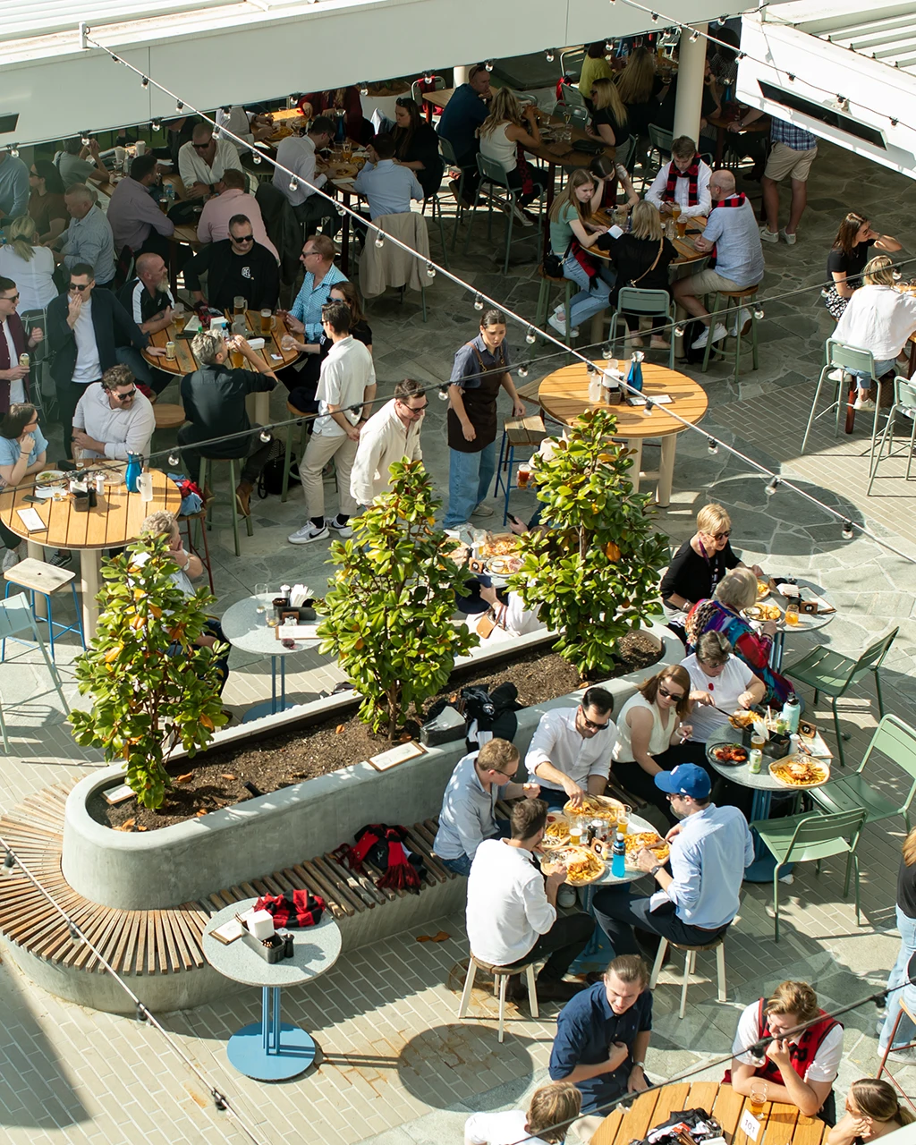 Bustling outdoor cafe with seating in sun and shade