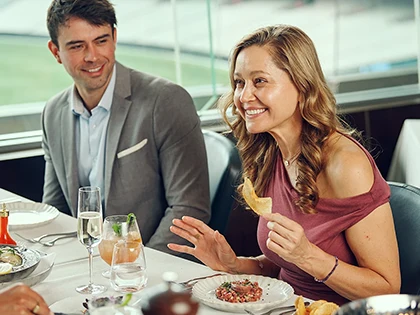 Two patrons enjoy formal dining with view of MCG turf
