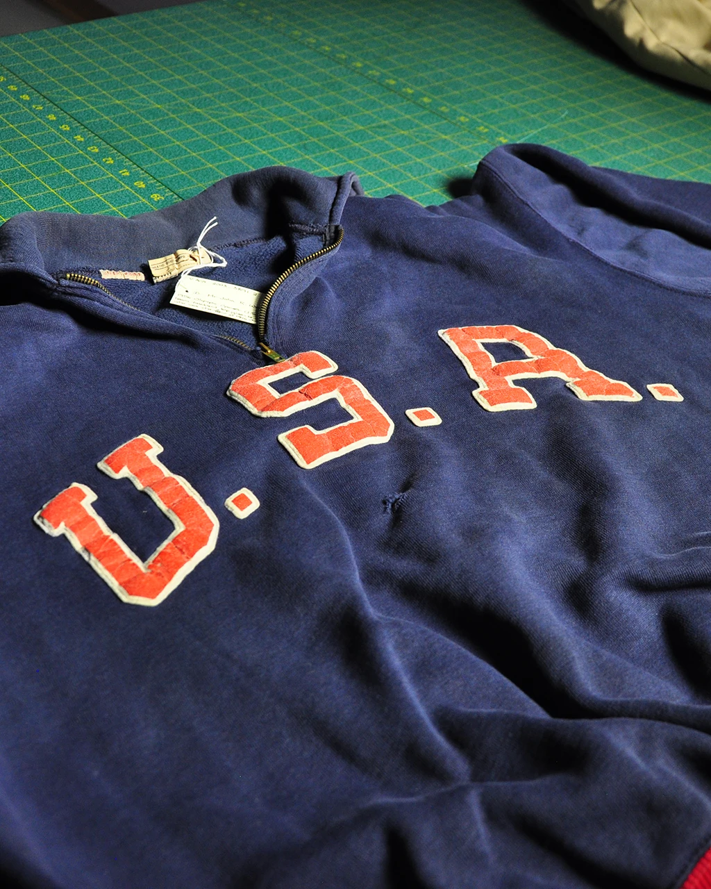 Vintage USA tracksuit top with red appliqué lettering, laid flat for cataloguing
