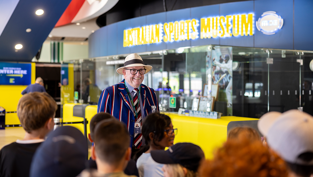 An MCG Tour Guide stands at the entry to the Australian Sports Museum