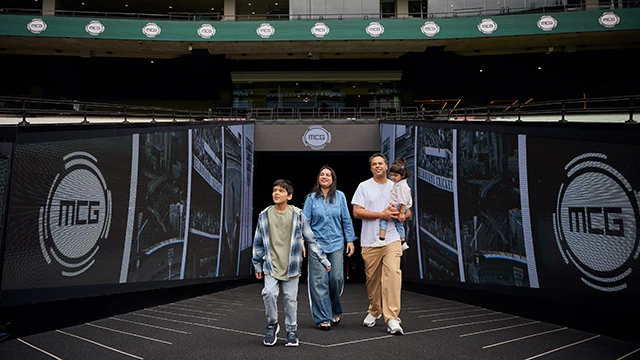 A family walks out onto the MCG boundary during a stadium tour