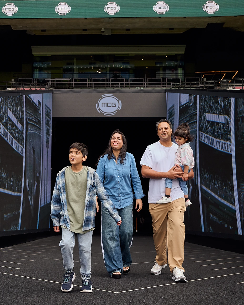 A family walks out onto the MCG boundary during a stadium tour