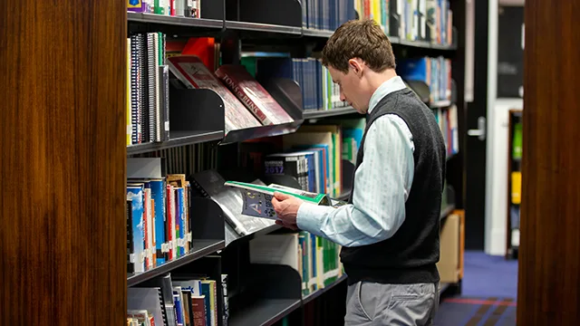 Person intently flips through a book in the library