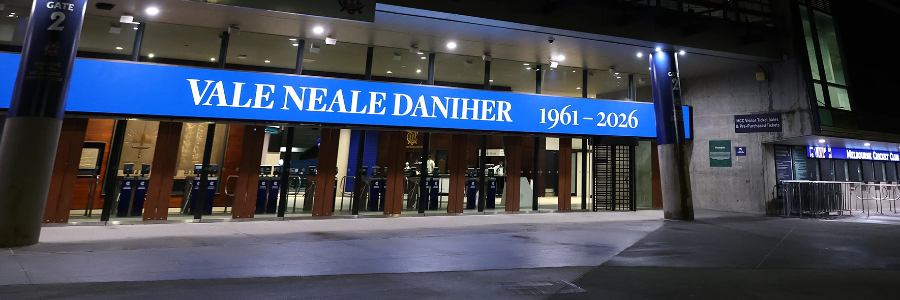 MCG at night displaying a tribute banner reading "Vale Neale Daniher 1961–2026"
