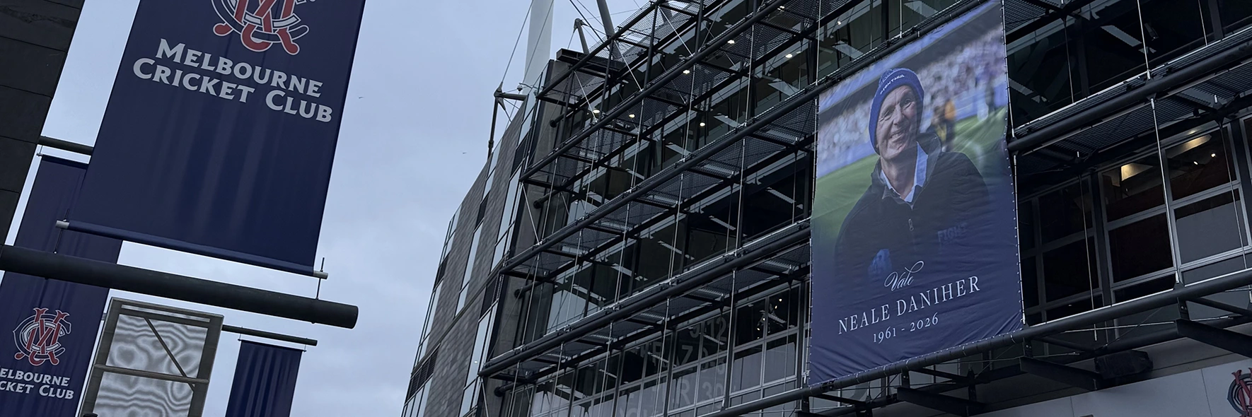 A tribute banner for Neale Daniher (1961–2026) displayed on the MCG exterior.