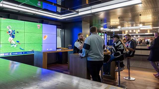 Fans drink beer next to the big screen in the Haydn Bunton Sports Bar at the MCG