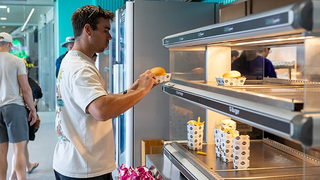 A patron selects a burger from the MCG Food Store