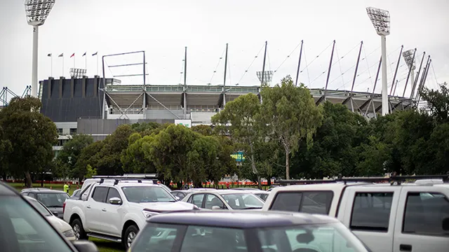 Cars parked in parkland in front of the stadium