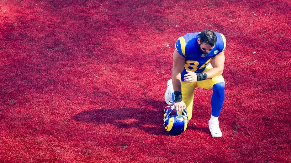A LA Rams player kneels with his helmet in the red end zone at the MCG