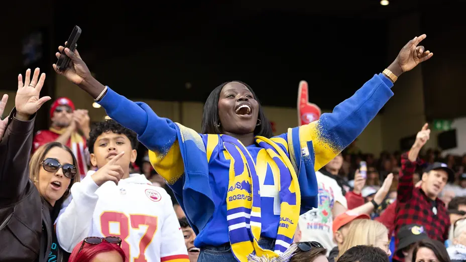 A Rams fan celebrates with arms outstretched in the MCG crowd