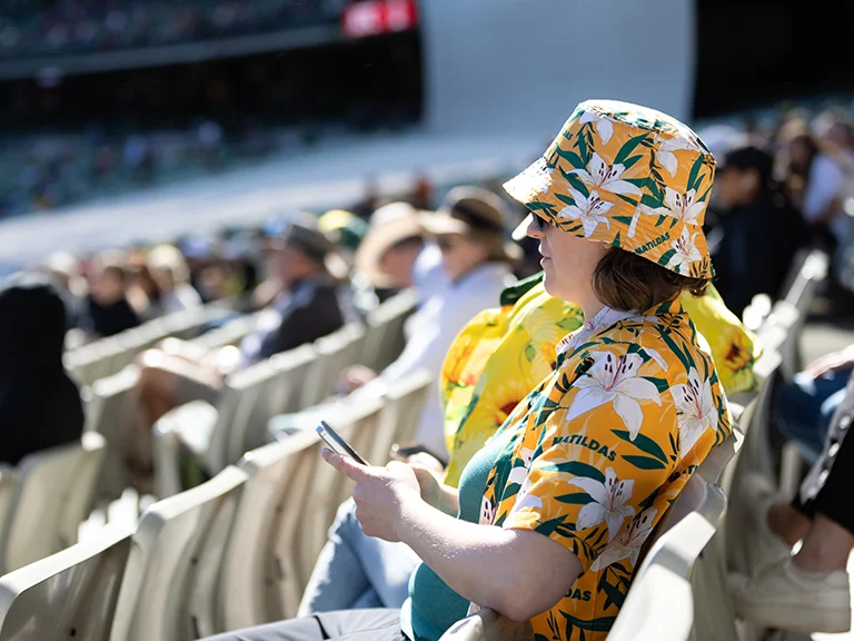 Patron using mobile phone and wearing green and gold