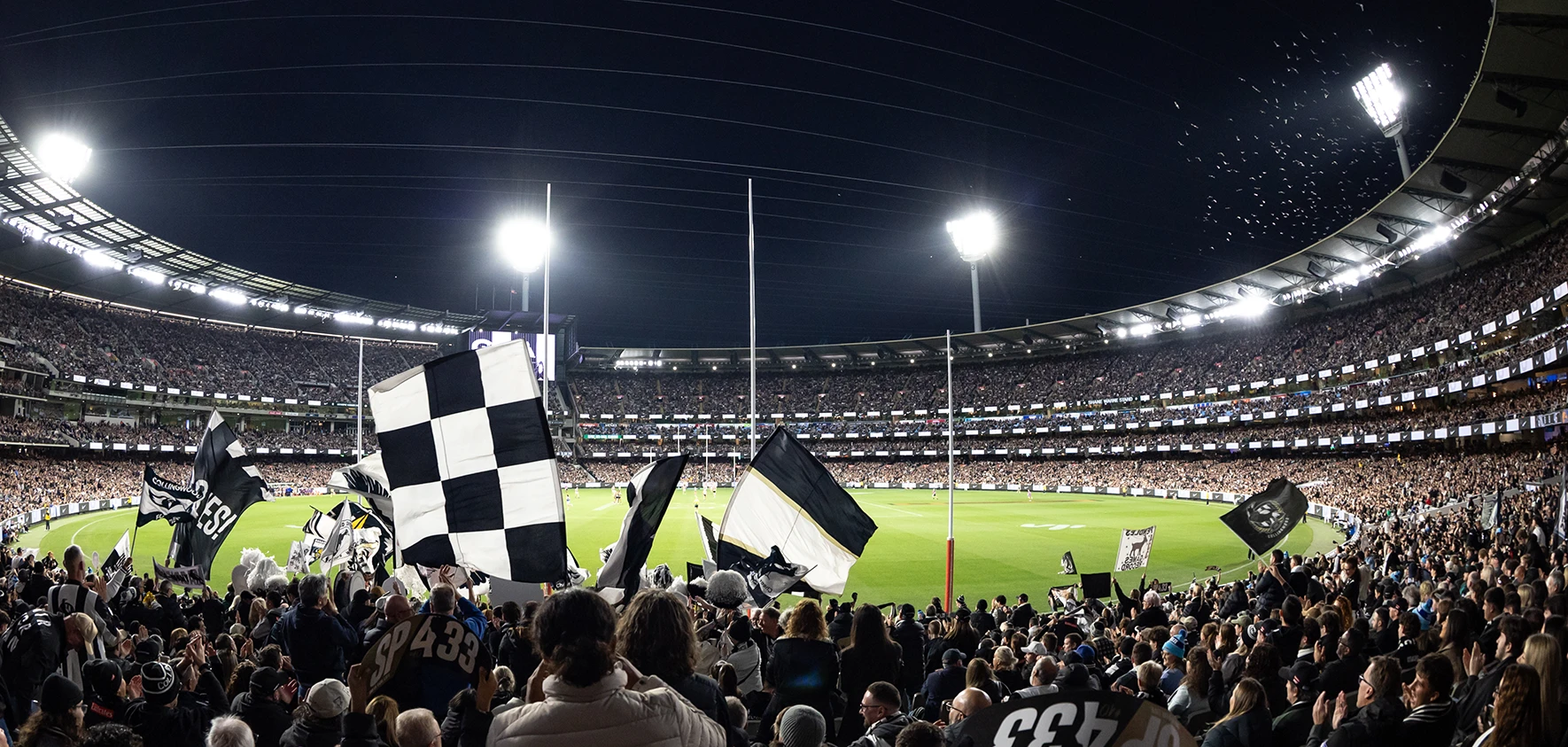 Collingwood fans wave flags behind the goals at a packed MCG