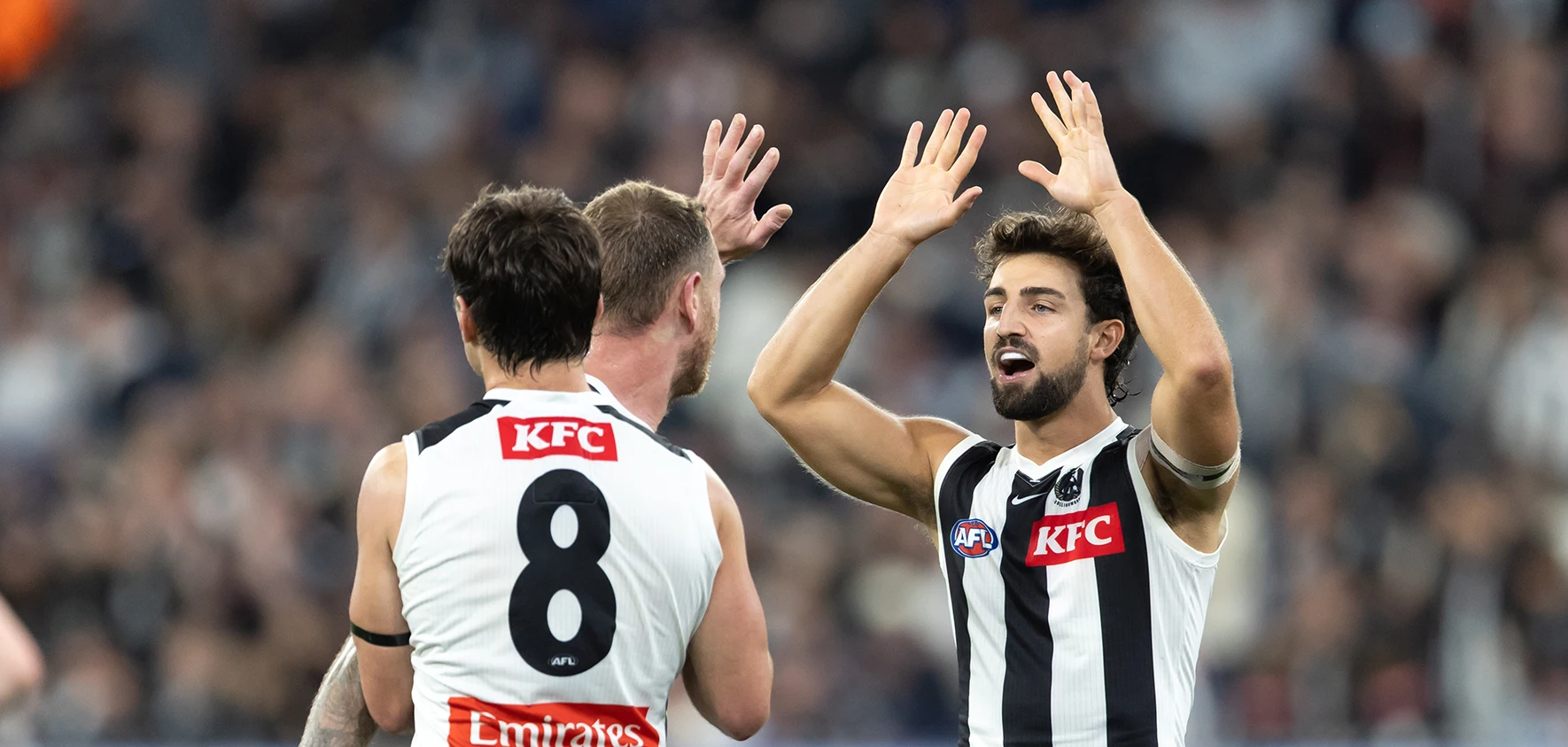 Josh Daicos high-fives Collingwood teammates