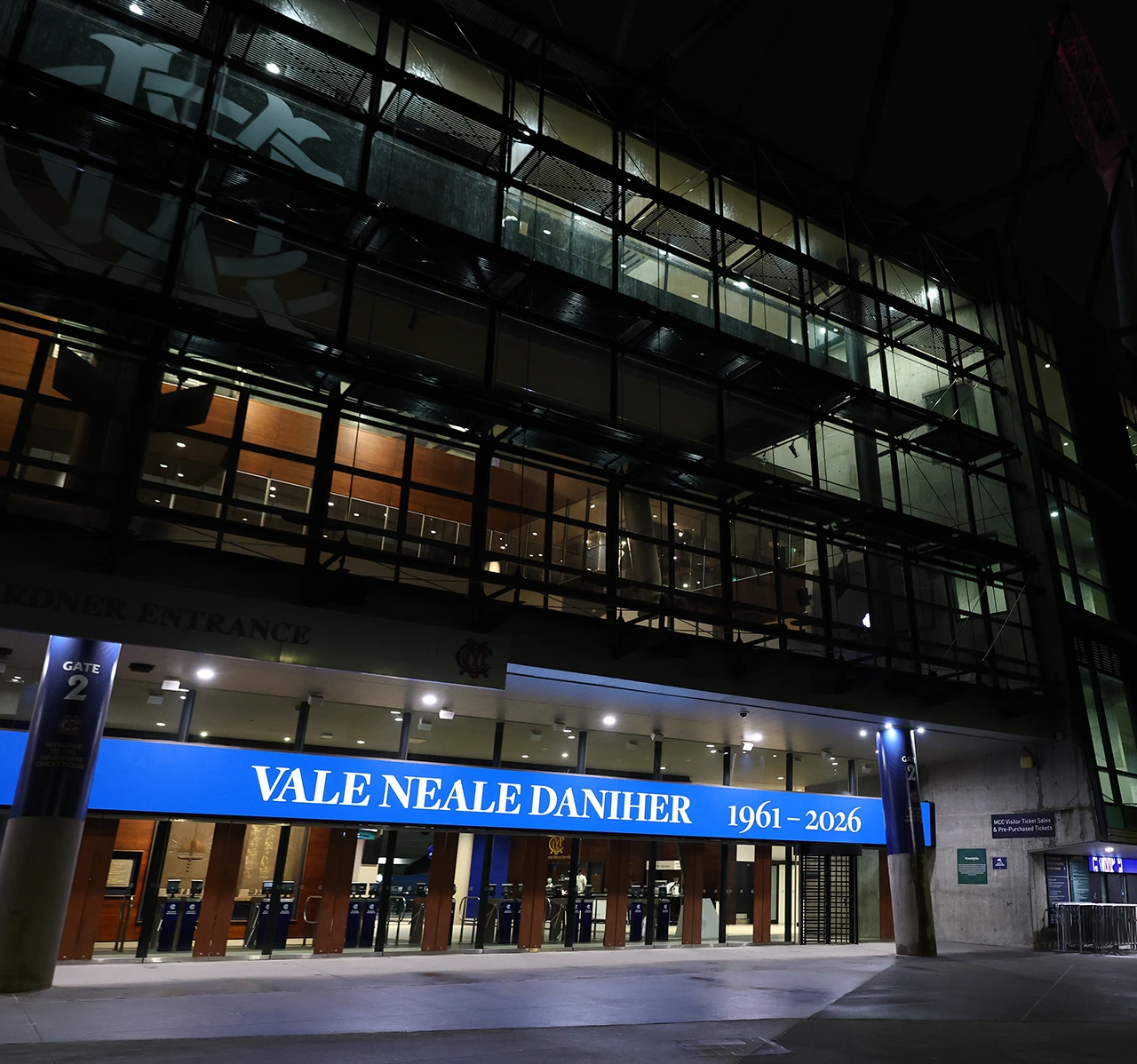 MCG at night displaying a tribute banner reading "Vale Neale Daniher 1961–2026"
